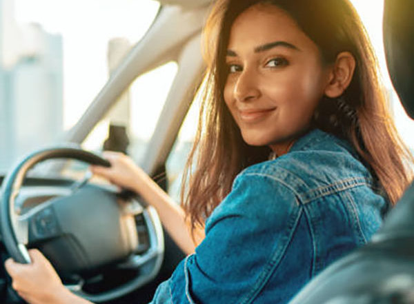 beautiful hispanic or indian female driver giving a welcome smile to passenger